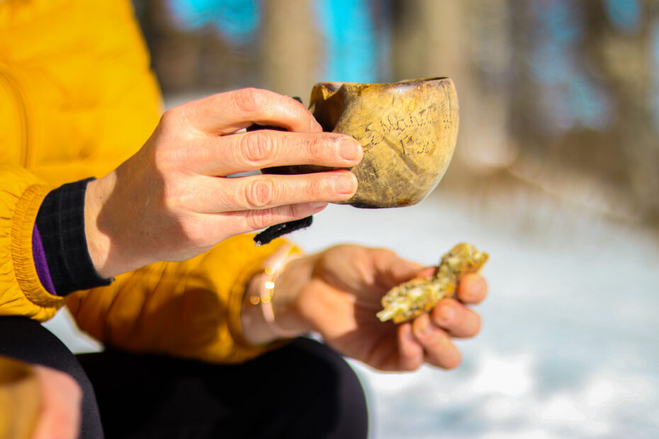 Henkilöllä kädessään kuksa ja voileipä.
